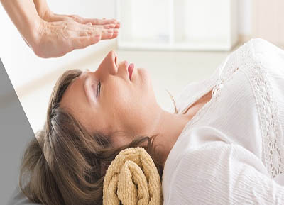 Mujer acostada le estan realizando un masaje holistico
